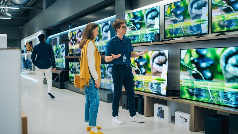 a woman looking at different tvs