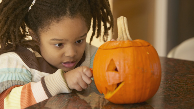 Little girl carving a pumpkin