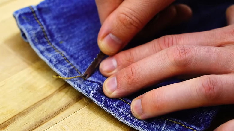 Using fish scaler to remove stitch from jeans