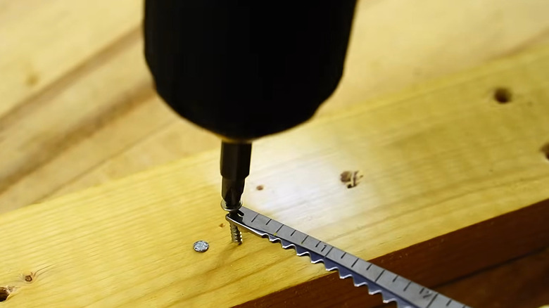 Fishing tool holding screw in place as drill puts it in wood