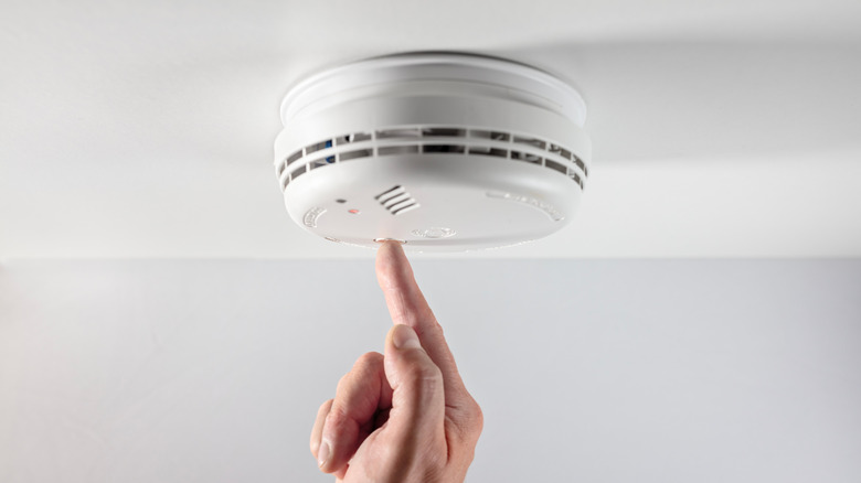 Person pushing button on smoke alarm