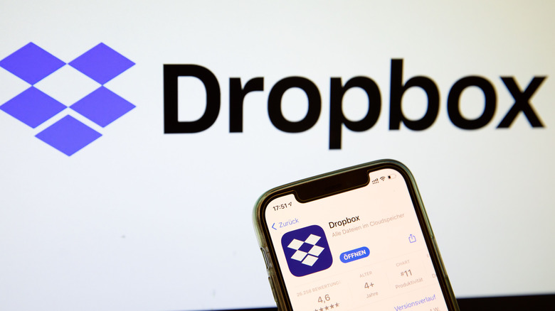 iPhone showing the Dropbox App Store page in front of the Dropbox logo.