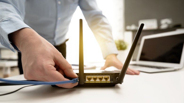 man checking cable connection on back of router