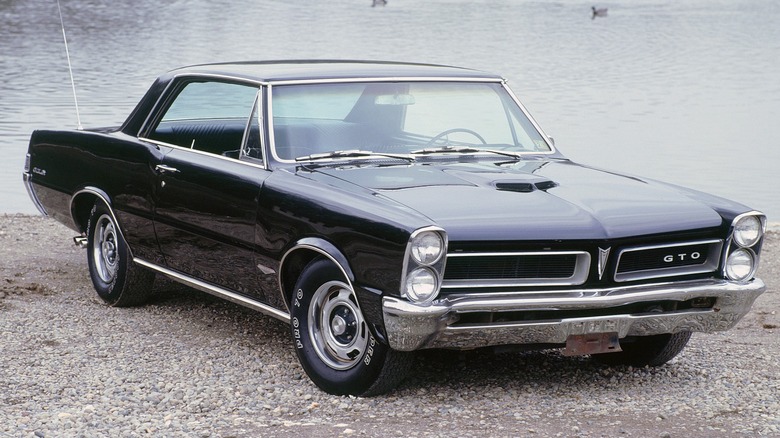 Black Pontiac GTO parked next to a lake