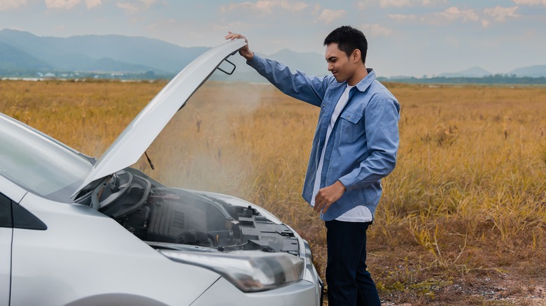 Man looking at overheated engine