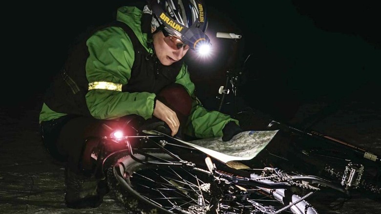 A woman using a Braun headlamp to see in the dark while she reads a map