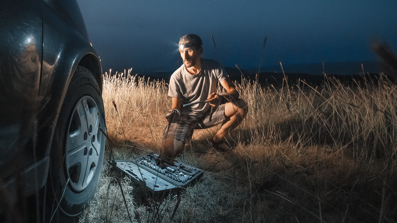 A man changing a tire in the wild.