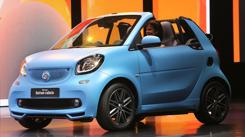 A Smart Fortwo Cabrio in baby blue at an auto show, front 3/4 view