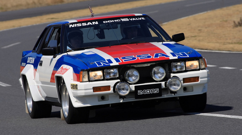 The Nissan 240RS driving on tarmac, front 3/4 view