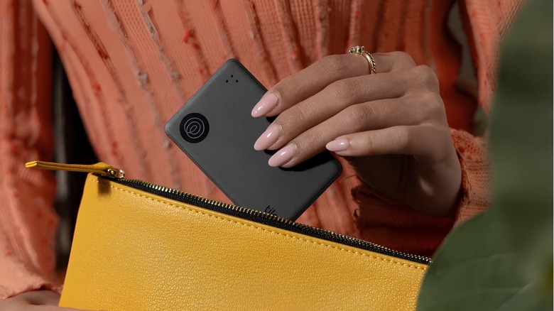 A person places the Tile Slim Bluetooth tracker inside a handbag