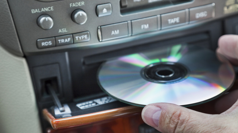 A Man Inserting A CD Into A Player In The Car