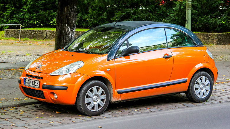 An orange Citroen C3 Pluriel with black roof pillars, front 3/4 view