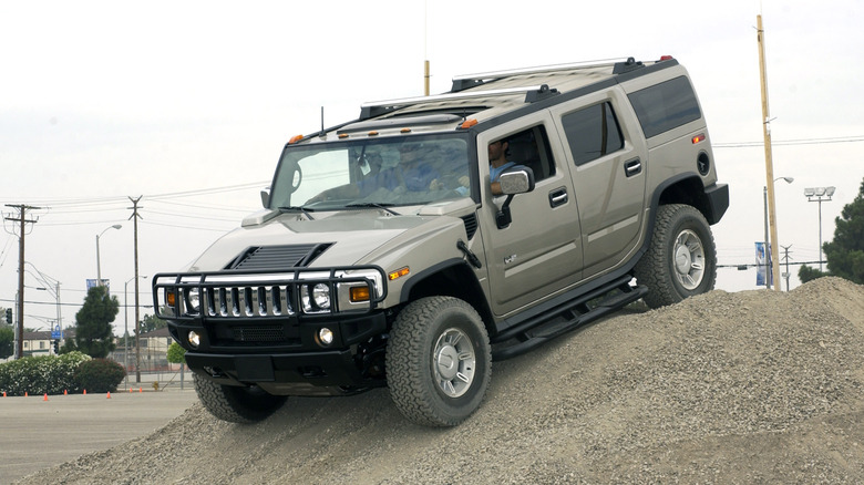 The Hummer H2 climbing over a sand dune, front 3/4 view