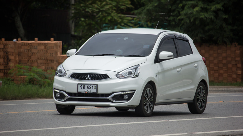 A white Mitsubishi Mirage on the move, front 3/4 view