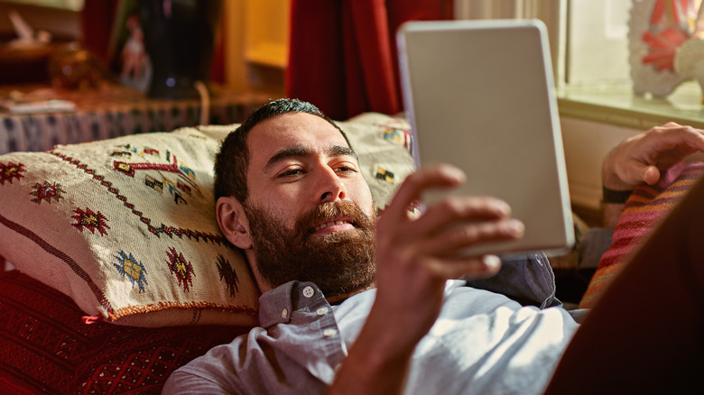 Man lying down looking at the screen of a handheld device