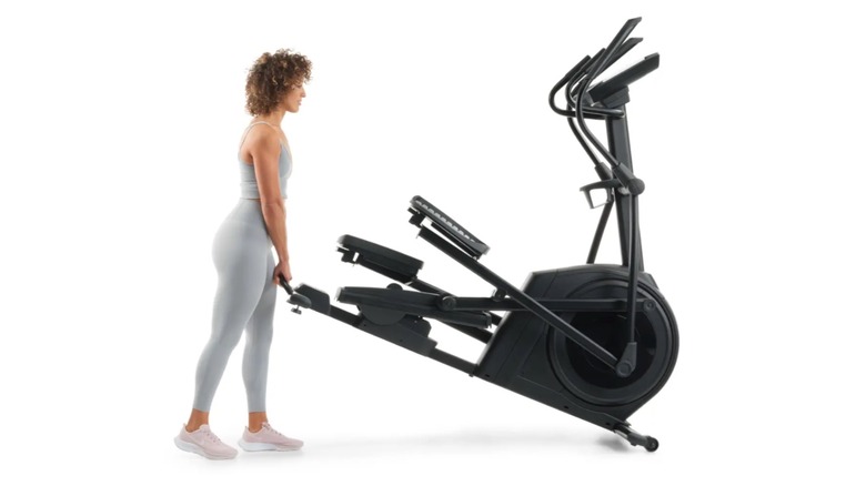 A woman lifting the backend of the NordicTrack AirGlide 14i.