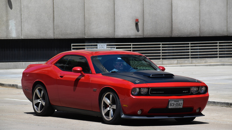 A pre-facelift third generation Dodge Challenger in red, front 3/4 view, matte black hood with scoop