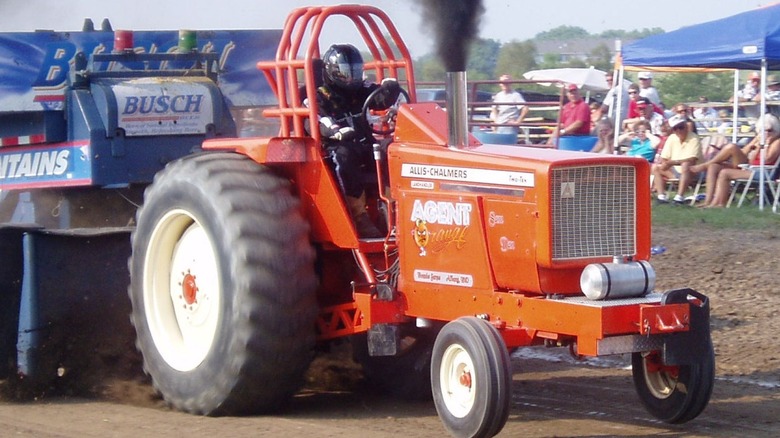 Competitive orange tractor pull in front of crowd