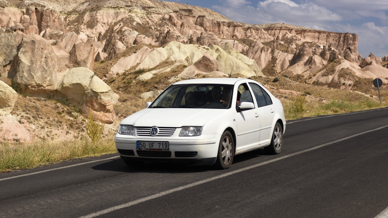 A Volkswagen Bora in white on the highway, front 3/4 view