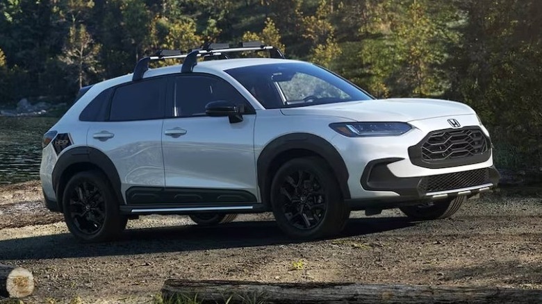 Platinum white pearl 2025 Honda HR-V parked in front of a water body with trees in the background