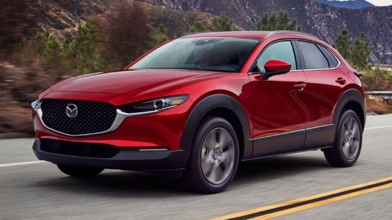 Red 2025 Mazda CX-30 driving on a road with mountains in the background