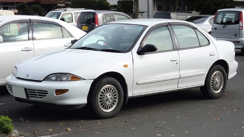 A white Toyota Cavalier parked with several other cars in the background.