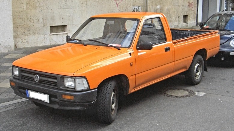 An orange 1987-1991 Volkswagen Taro parked on a street in front of a building