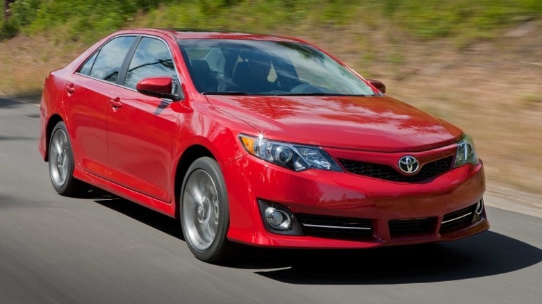 Front 3/4 shot of a red 2012 Toyota Camry SE driving on a road