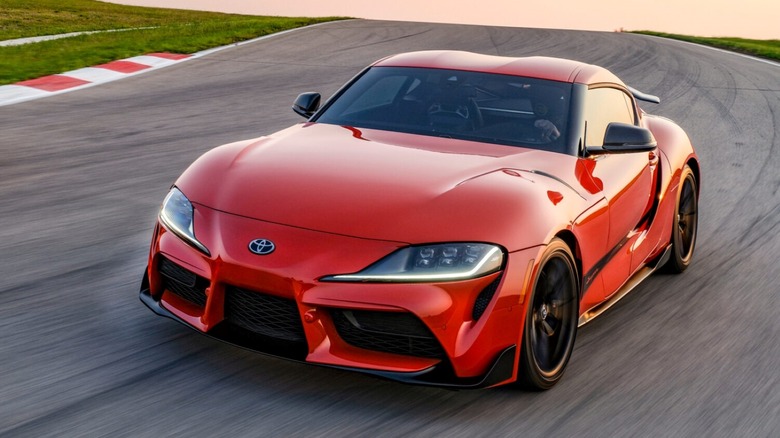 Front 3/4 shot of a red Toyota GR Supra driving on a track