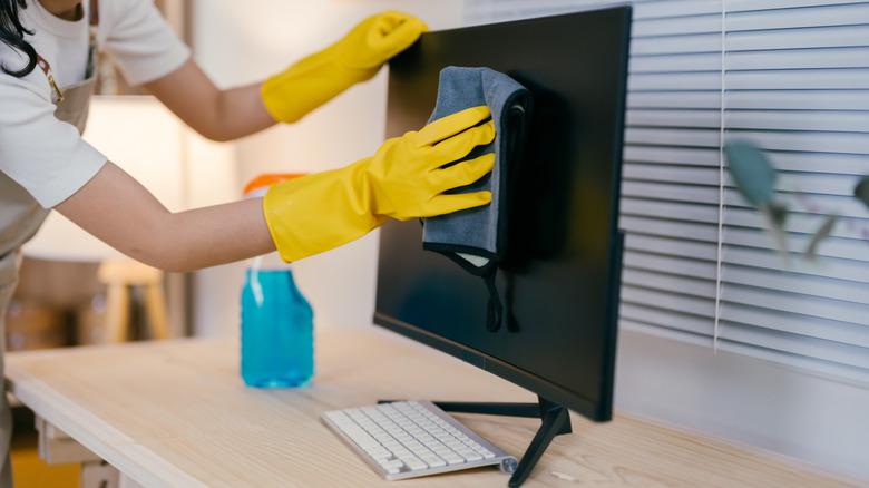 Cleaning a monitor with a microfiber cloth.