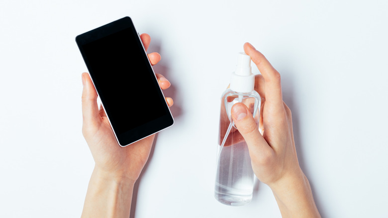 Spraying disinfectant on a smartphone.