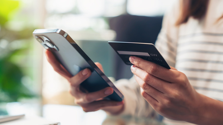 Woman holding an iPhone and a credit card. 