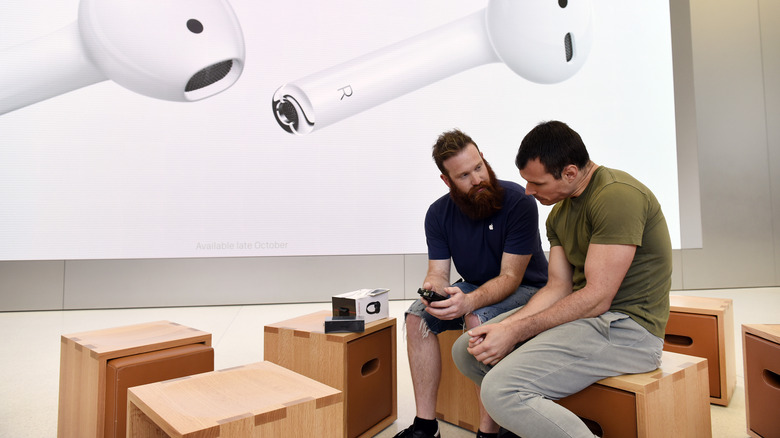 Apple employee talking to customer in Apple Store seating area.