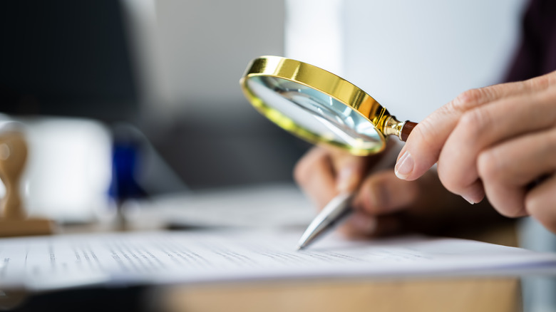Person doing paperwork using a magnifying glass