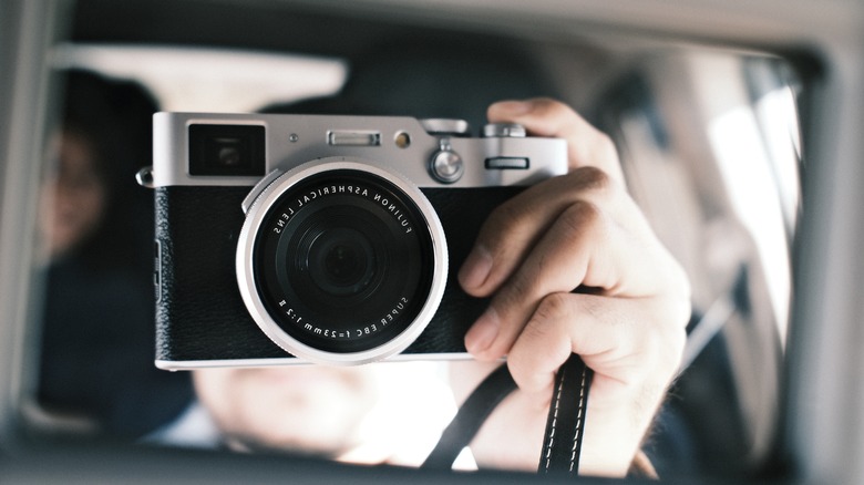 Holding a Fujifilm X100VI camera in a car mirror