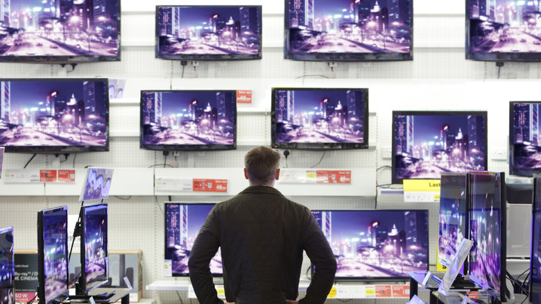 man looking at display TVs