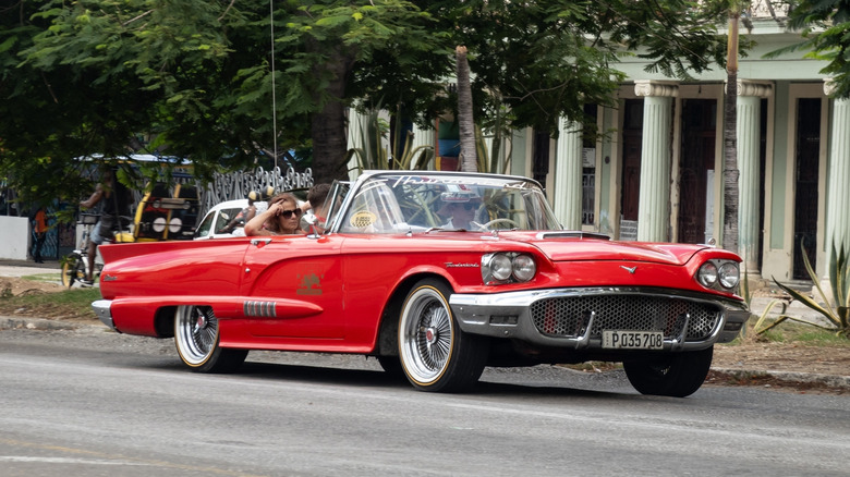 Red 1958 Ford Thunderbird driving on streets