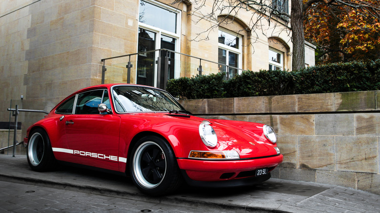 A Singer Porsche 911 in red with white stripes, front 3/4 view