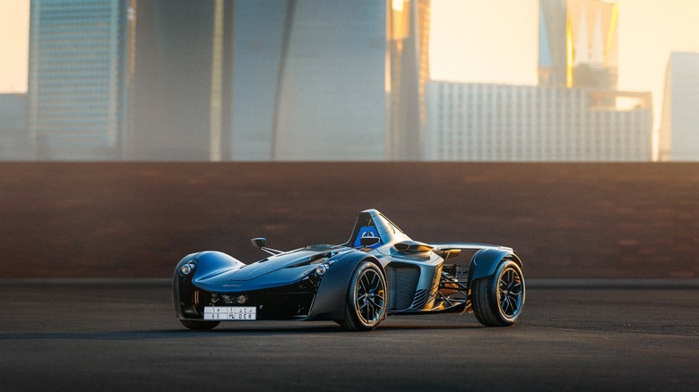 The BAC Mono in blue parked in front of modern skyscrapers.