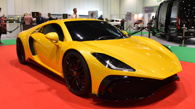 The Noble M500 in yellow displayed at an indoor car show.