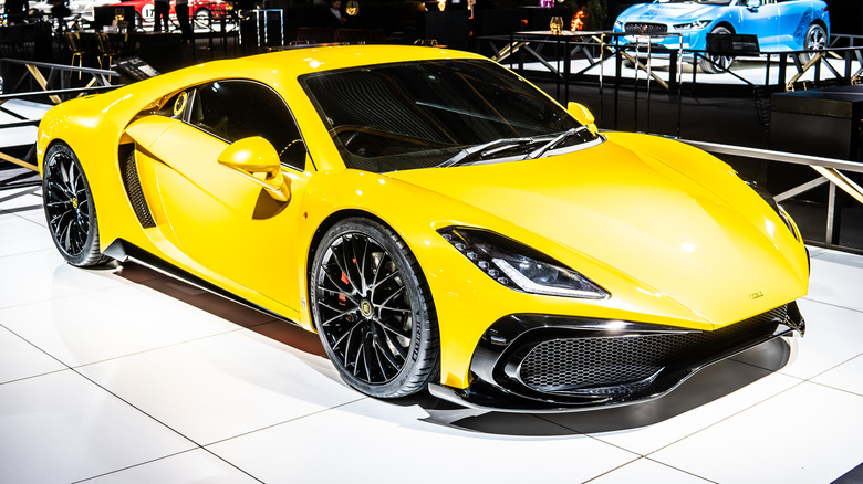 A yellow Noble M500 displayed indoors at a car show.