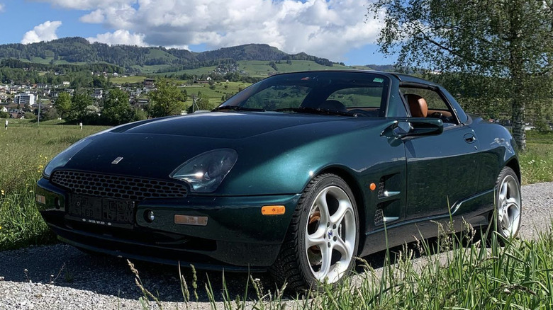 Qvale Mangusta parked on a scenic countryside road.