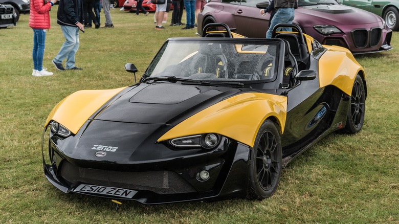 Yellow and black Zenos E10 displayed at an outdoor car show.