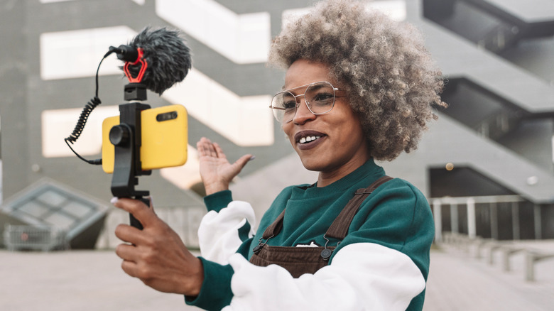 A woman recording herself on a smartphone with a mobile microphone attached.