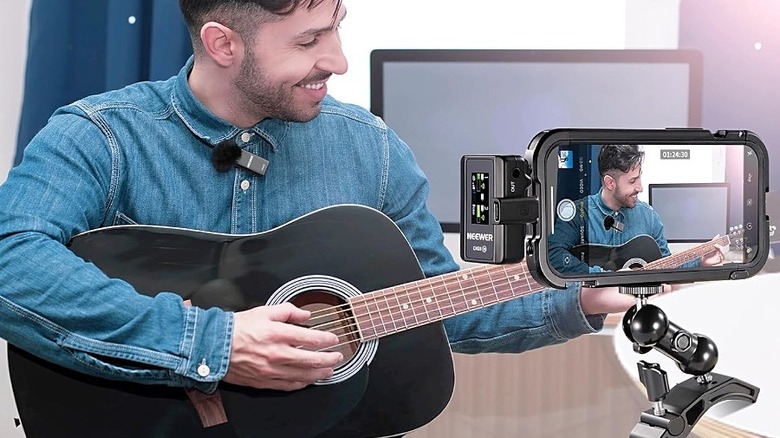 A man records himself playing guitar using a Neewer CM28 lavalier microphone.