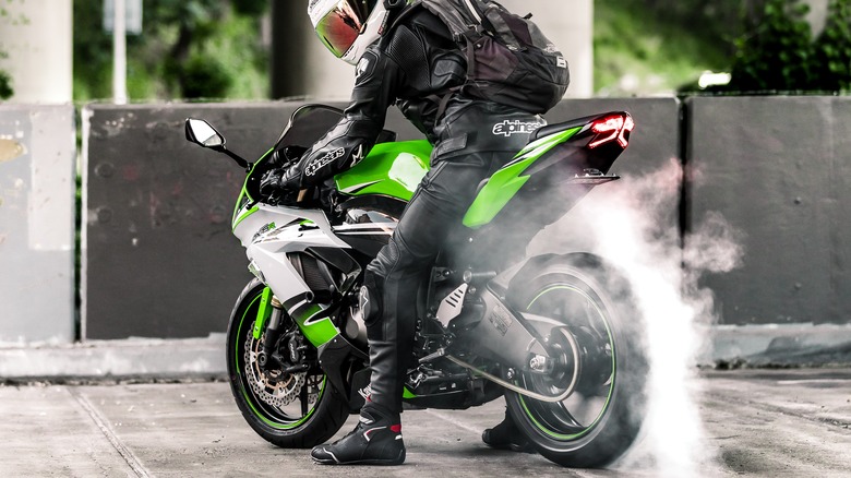 rider on green Kawasaki Ninja ZX-6R doing standing burnout