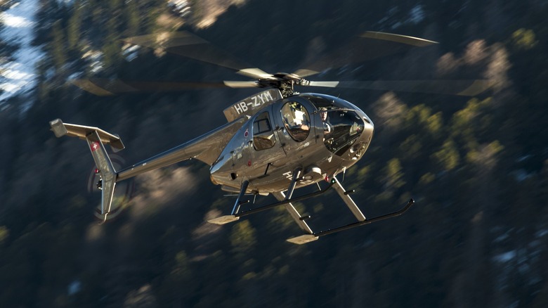 The MD500 helicopter flying over a forest.