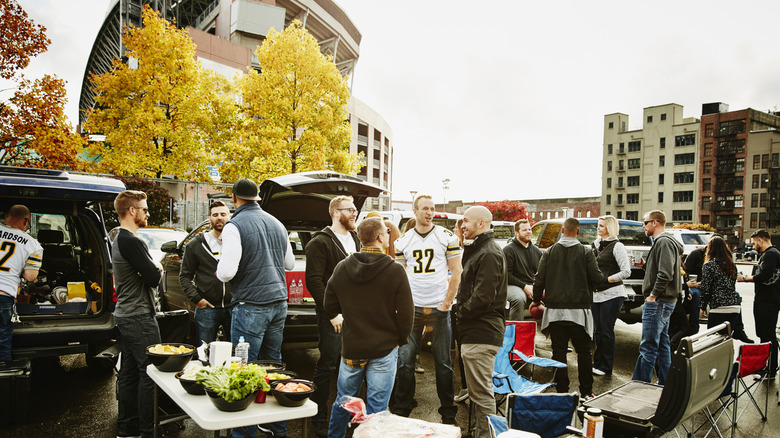 Group of people in a parking lot party outside a sports stadium