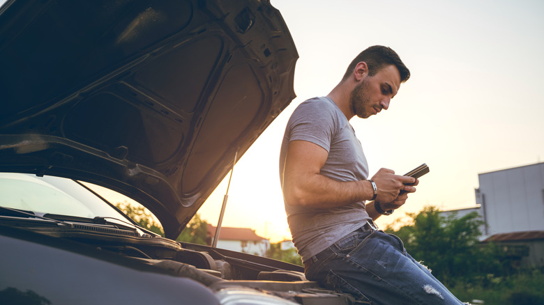 person sitting on car bumper