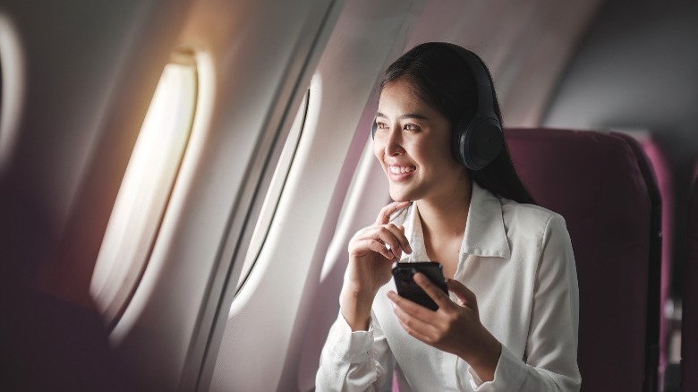 Woman wearing headphones on airplane